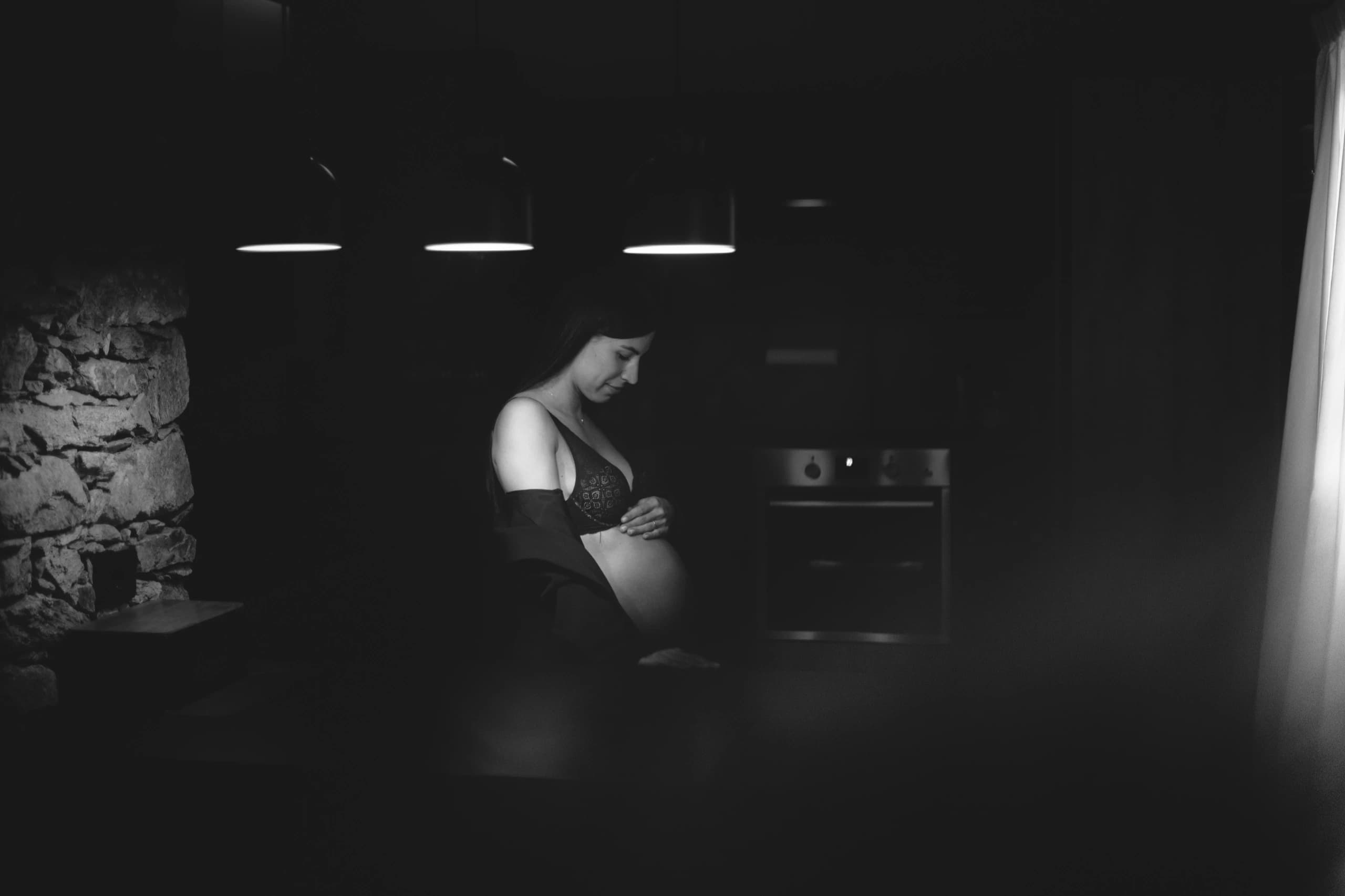 Donna in gravidanza raccolta in un ambiente domestico in bianco e nero