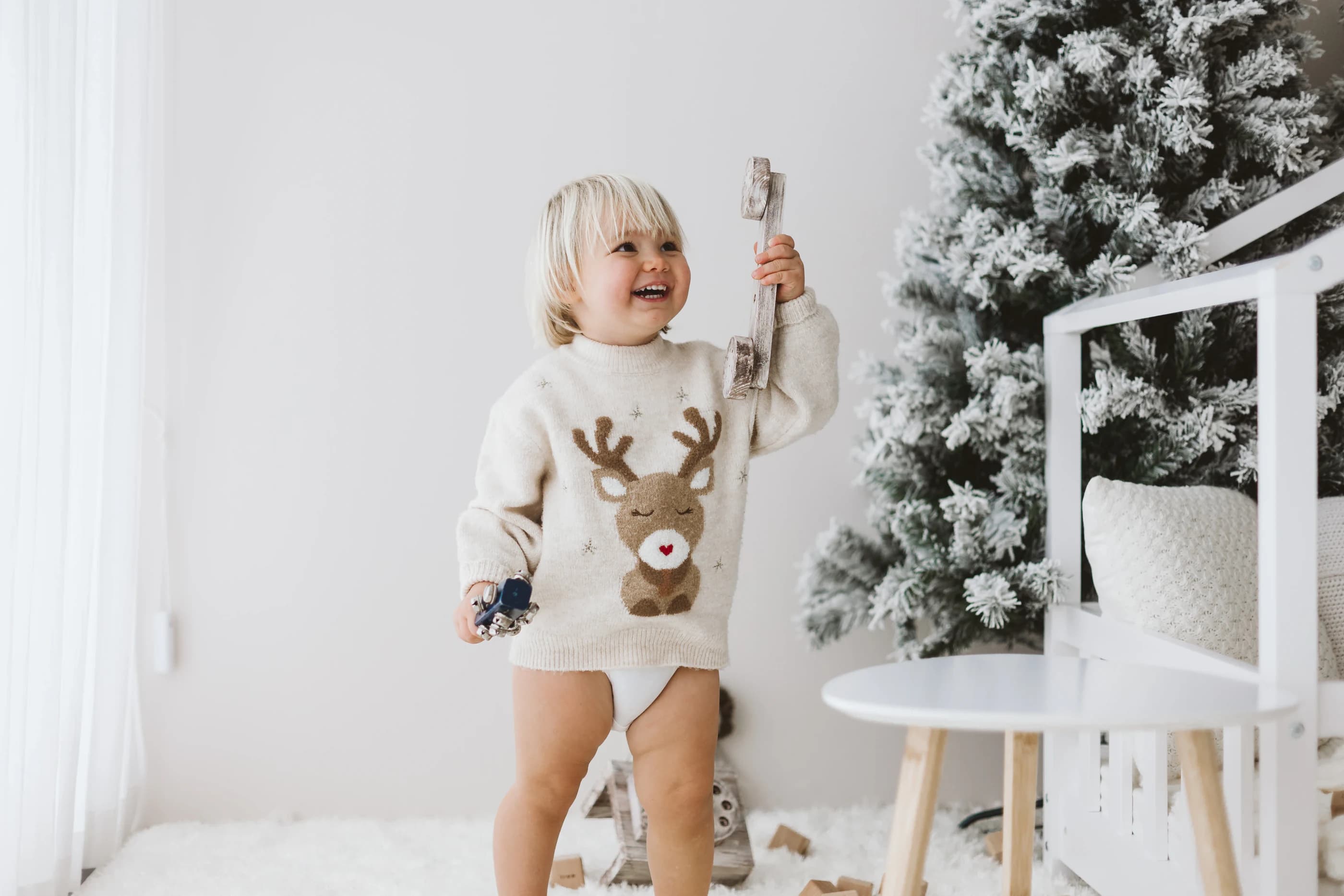 Un bambino sorride giocando accanto a un grande albero innevato