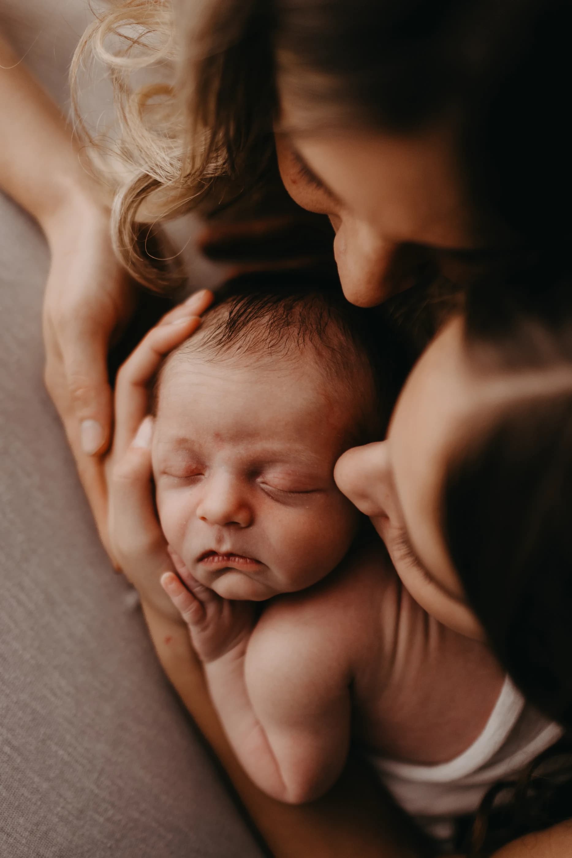 Neonato custodito tra le mani e i volti della sua famiglia