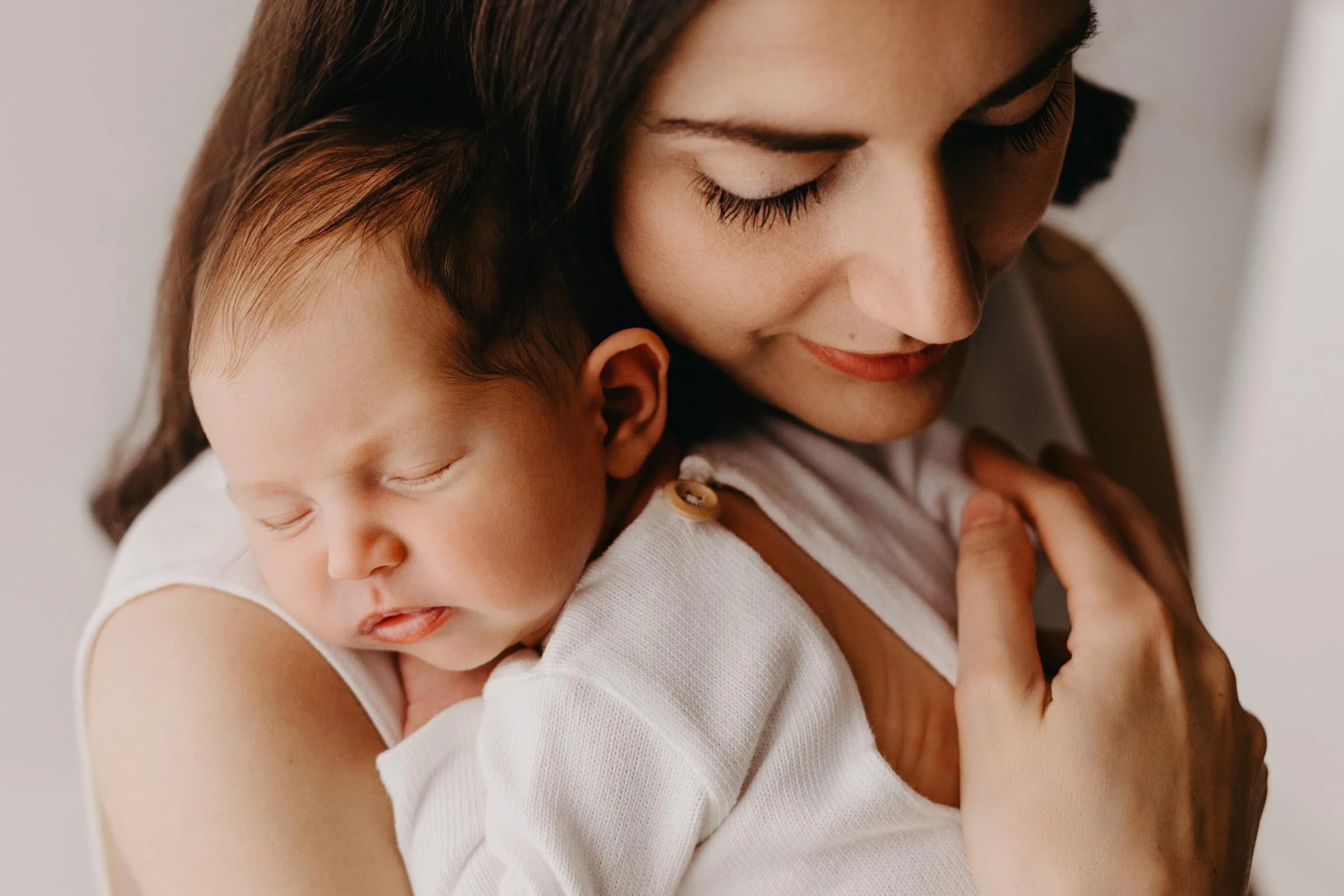 Madre che tiene il suo neonato addormentato vicino al viso