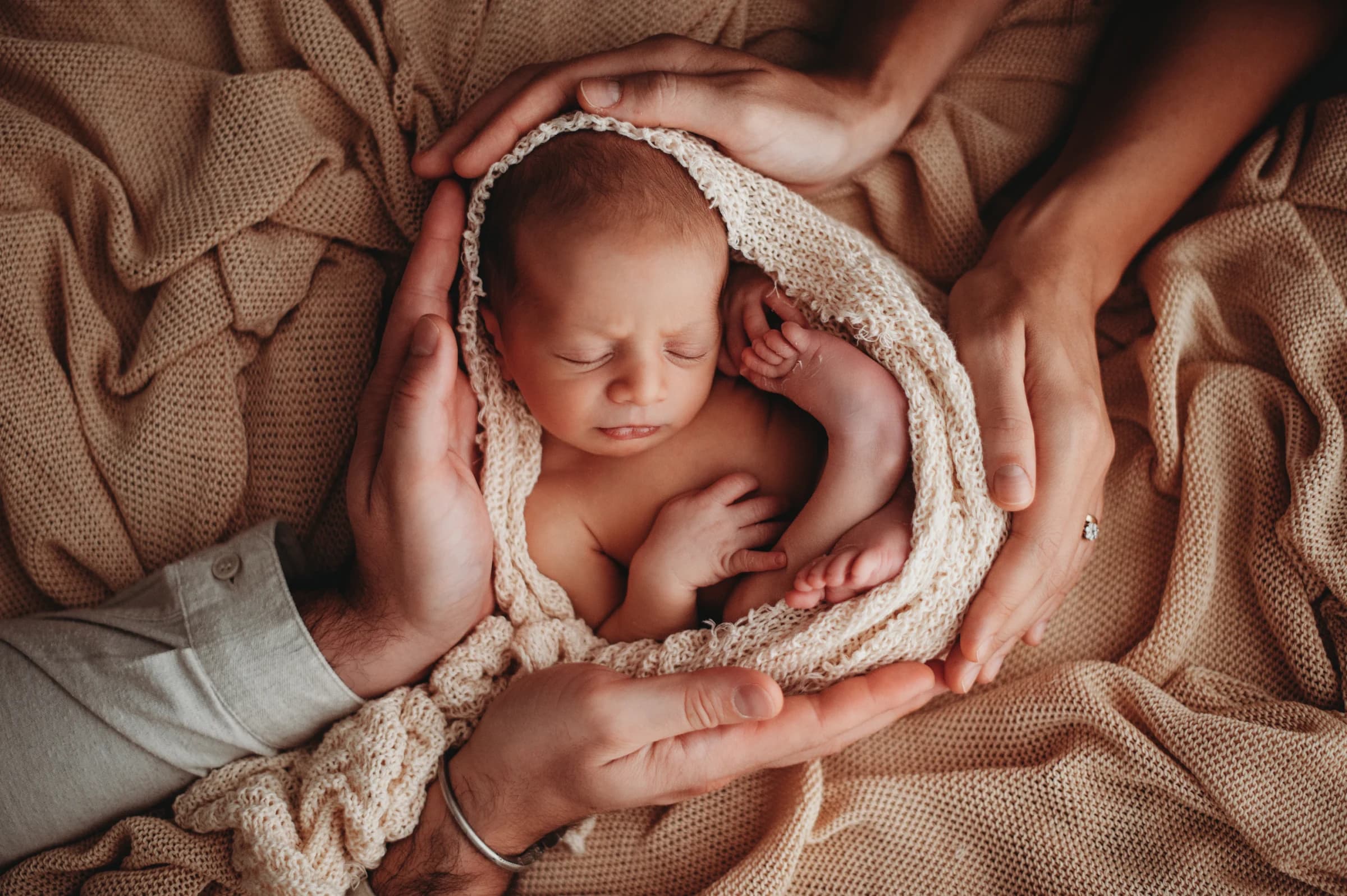 Neonato raccolto tra le mani della sua famiglia