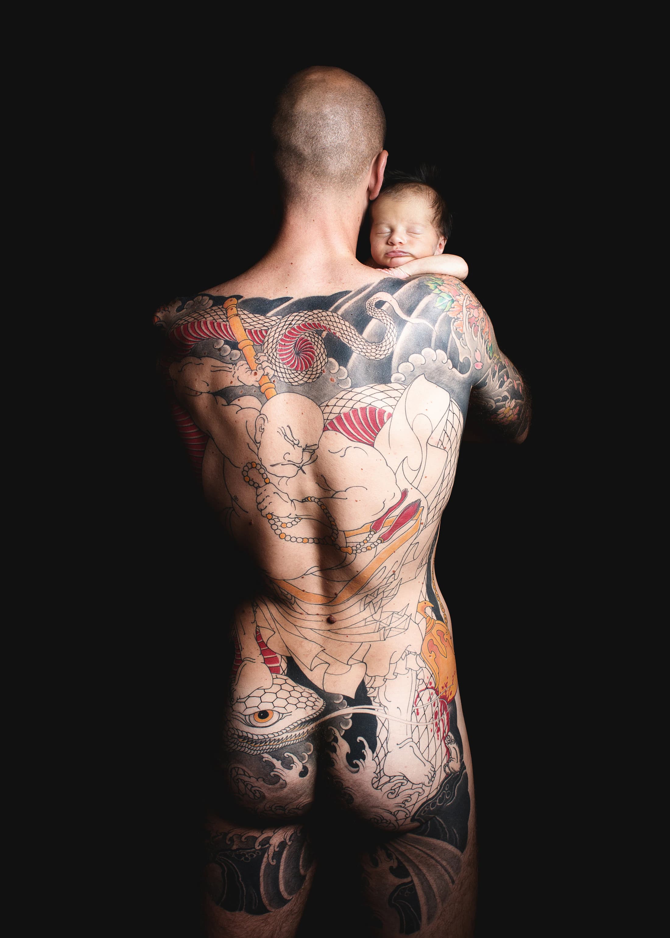 Padre tatuato che accoglie il neonato sulla spalla