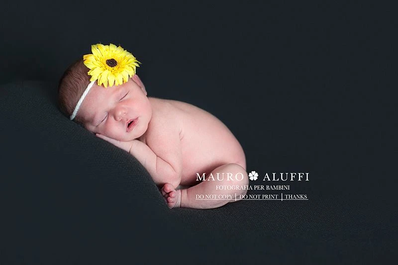neonato che dorme con fiore giallo in testa