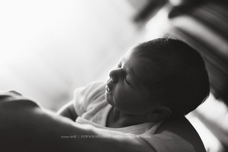 fotografo neonati Neonata addormentata in braccio a un adulto in una fotografia in bianco e nero