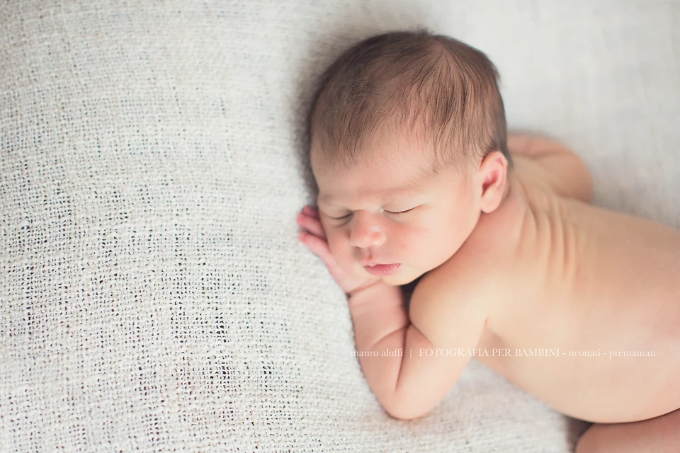 fotografo neonati Neonata addormentata a pancia in giù su un telo chiaro
