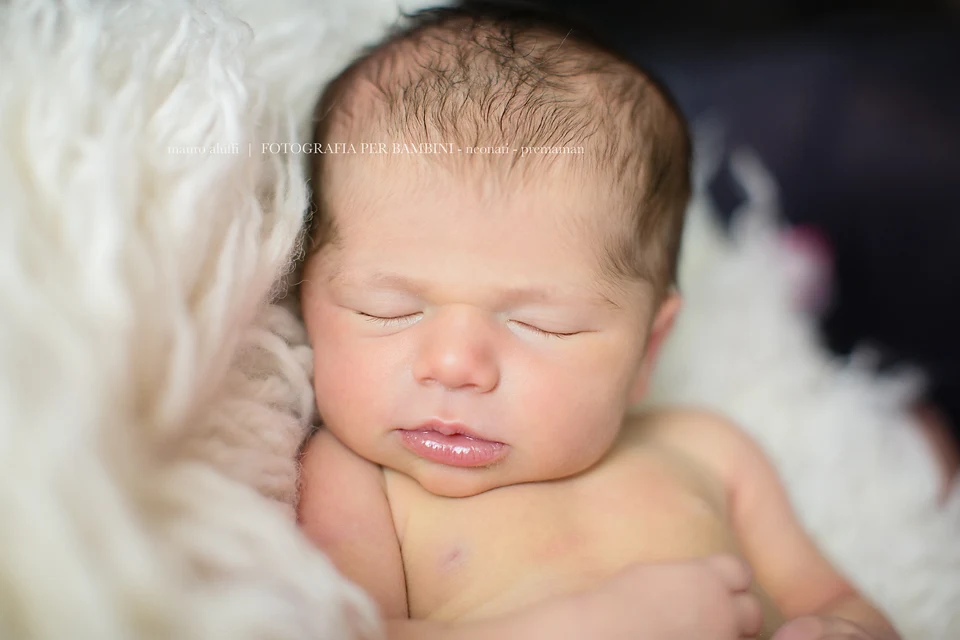 fotografo neonati cuneo Primo piano di una neonata addormentata su una coperta bianca