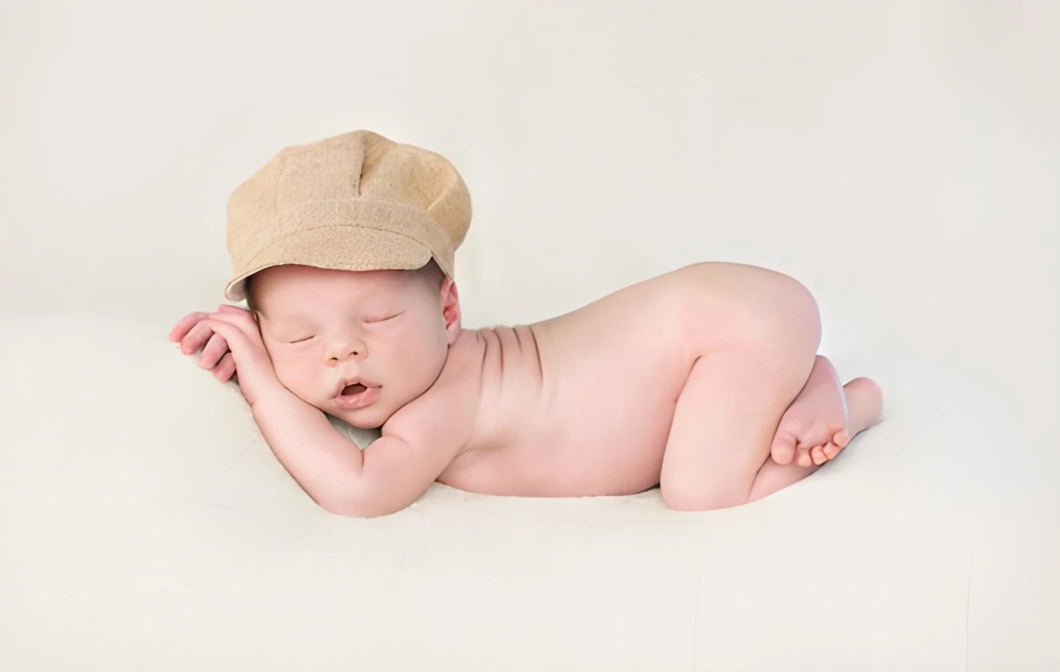 Neonato addormentato disteso con un cappello beige