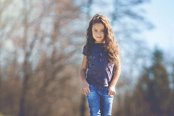 Bambina in piedi sul sentiero con il bosco alle spalle