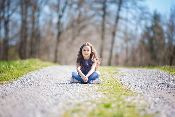 Bambina seduta su un sentiero insieme alla sorellina