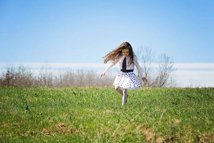 Bambina corre su una collina con le montagne sullo sfondo