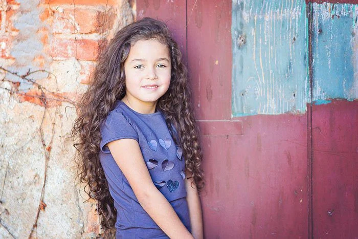 Bambina in piedi davanti a una porta colorata