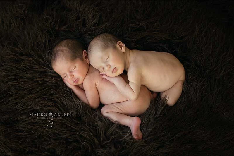 Due gemelli appena nati addormentati su una coperta scura