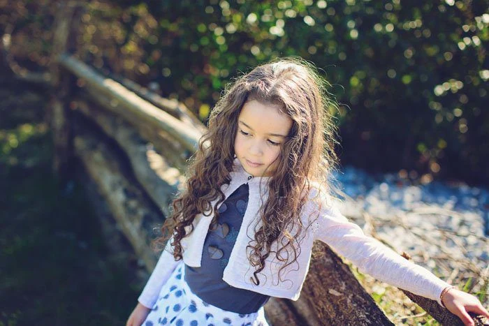 Bambina cammina accanto a una staccionata nel bosco