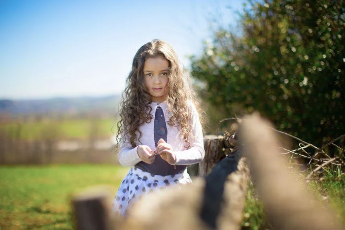 Bambina in piedi accanto a una staccionata