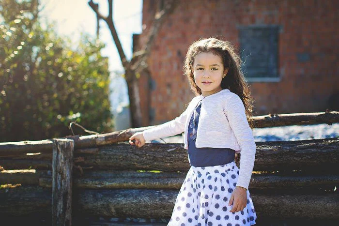 Bambina appoggiata a una staccionata di legno