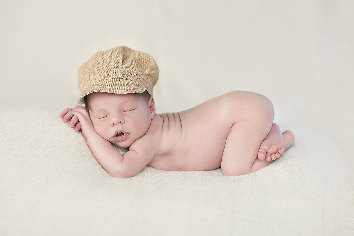 Neonato addormentato disteso con un cappello beige