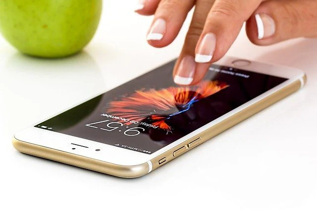 Mano che usa uno smartphone appoggiato su un tavolo